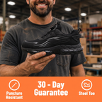 A man in a dark gray work shirt holds up a black athletic sneaker in a warehouse setting. An orange banner at the bottom features white text reading '30 - Day Guarantee' with icons for 'Puncture Resistant' and 'Steel Toe'.
